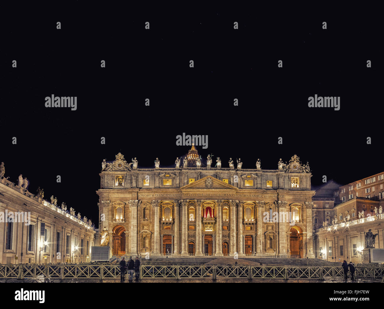 Vista notturna della facciata della chiesa nella città del Vaticano con porte sante, colonne e statua Foto Stock