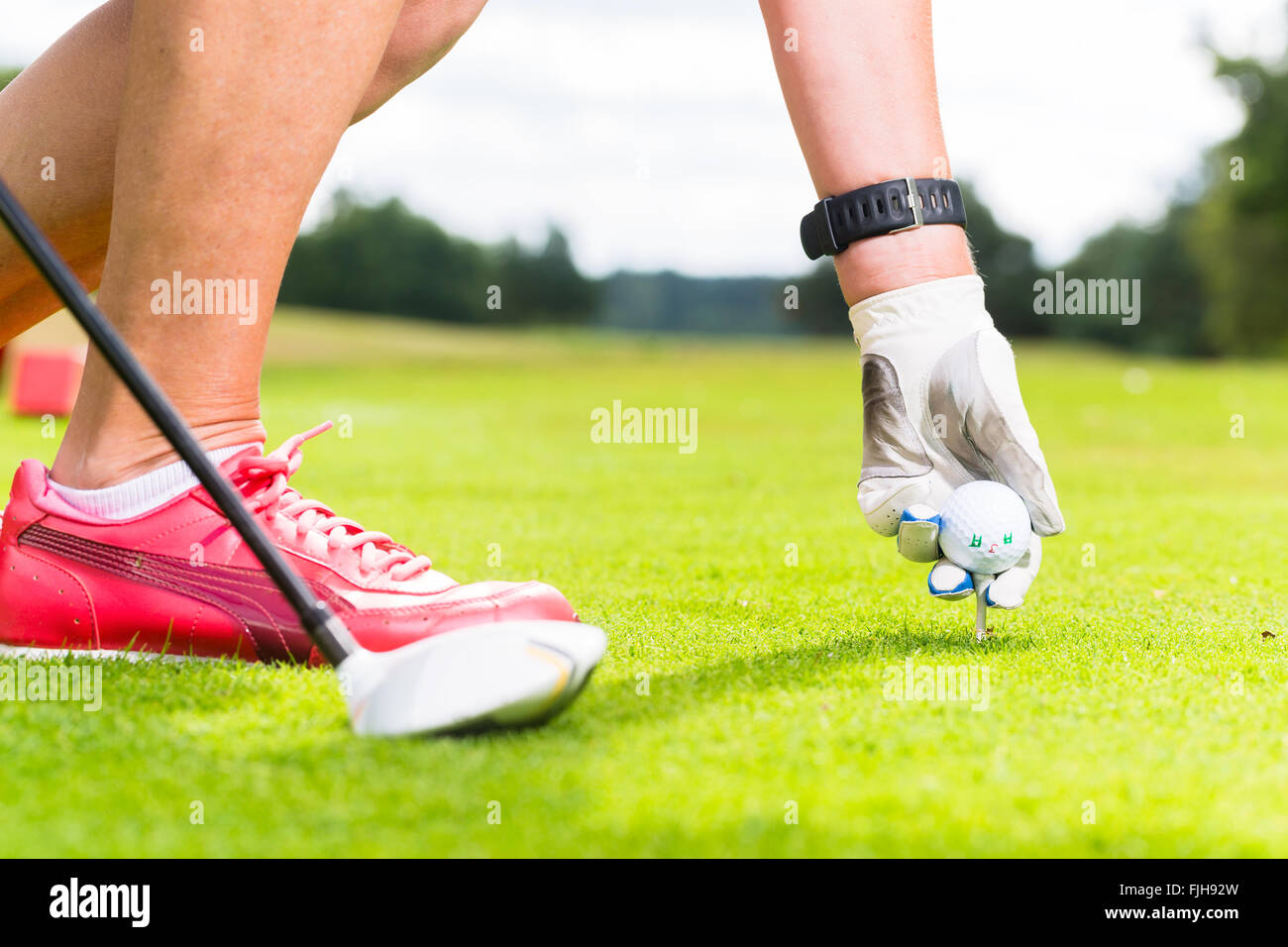 Donna di mettere la pallina da golf sul raccordo a T vicino shot Foto Stock