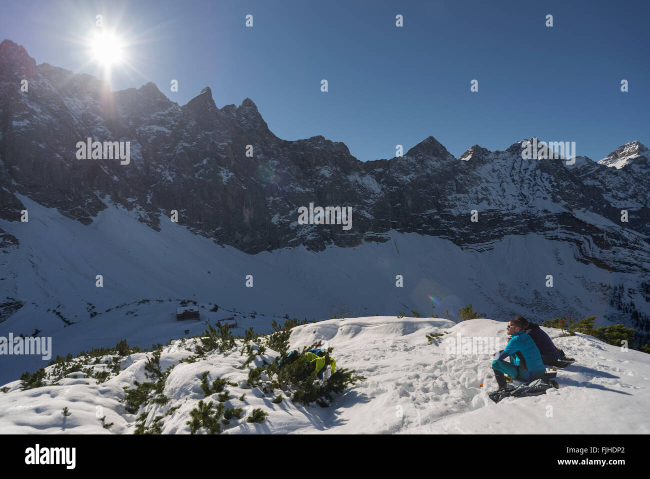 Gli alpinisti seduto su un pendio di montagna in mezzo alla neve di prendere il sole e guardare alla montagna Karwendel gamma,Tirol,Austria Foto Stock