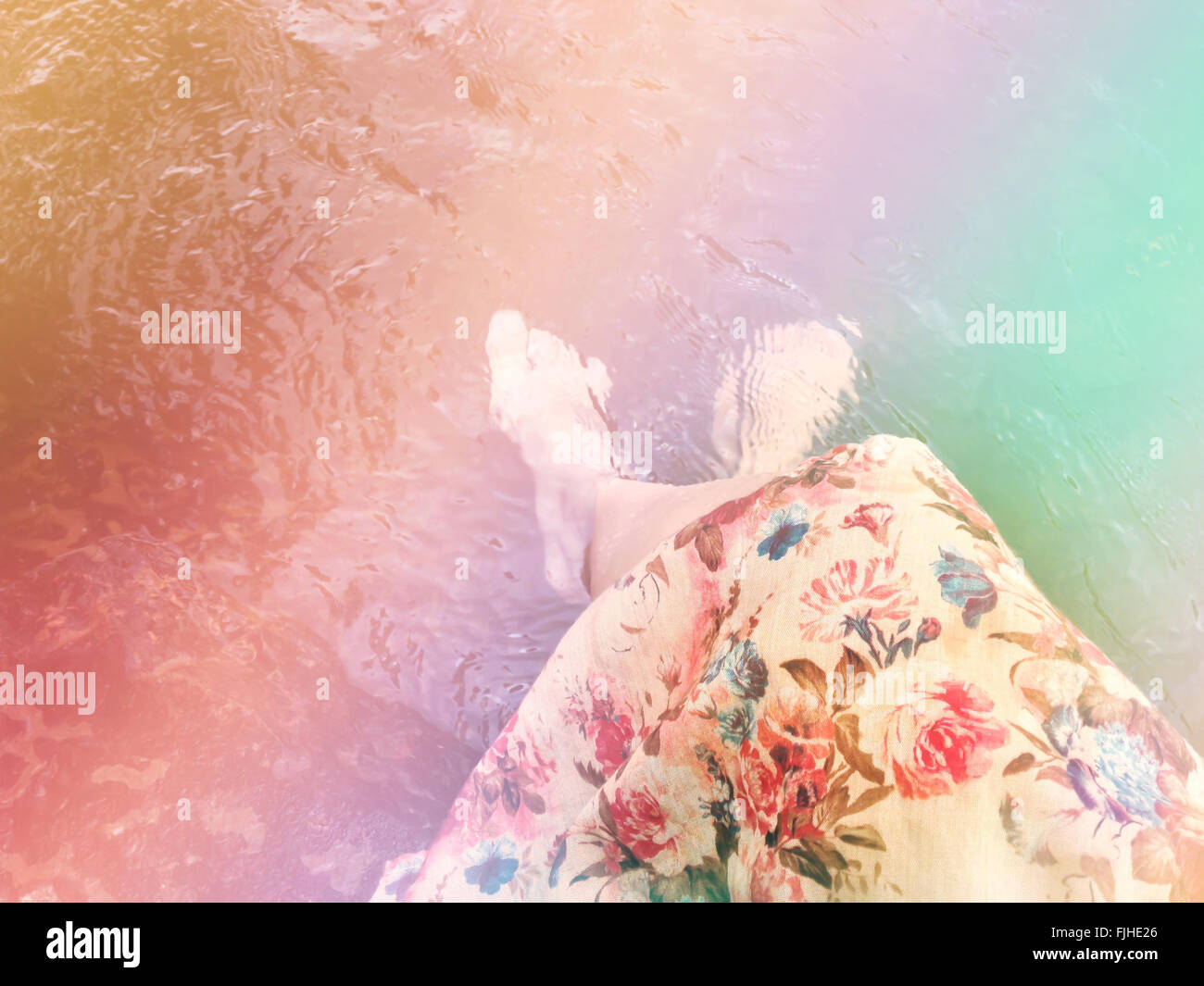 Sognante colore fantasia stile di vita, le donne in abito di fiori di sedersi e immergere i piedi nel flusso cristallino, estate rilassante sensazione Foto Stock