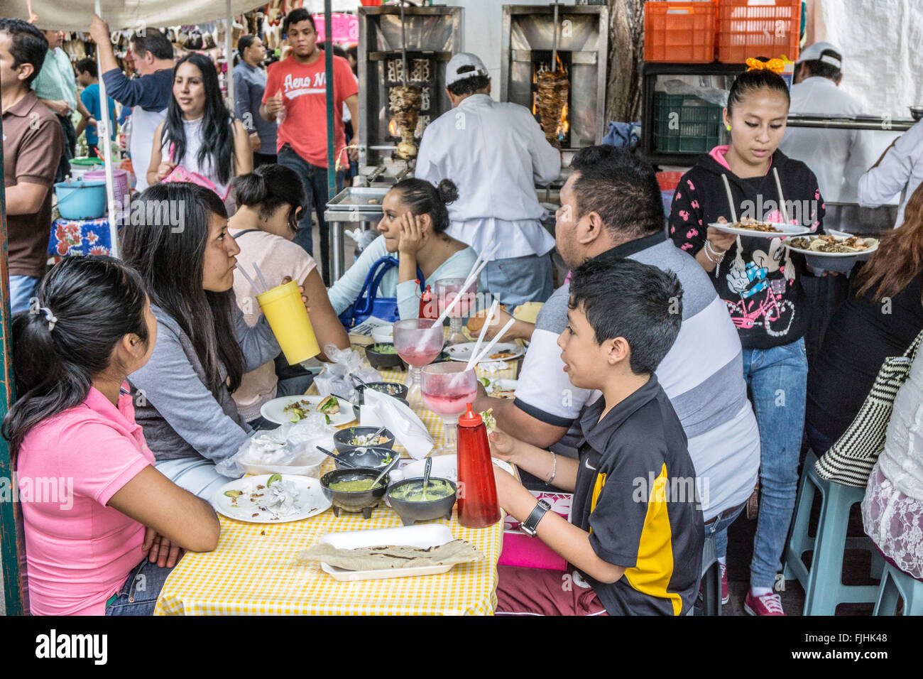 Famiglia siede a tavola nel sedersi cibo stallo a Llano Park mercato del venerdì con cook in background come teen cameriera spreme dalla Foto Stock