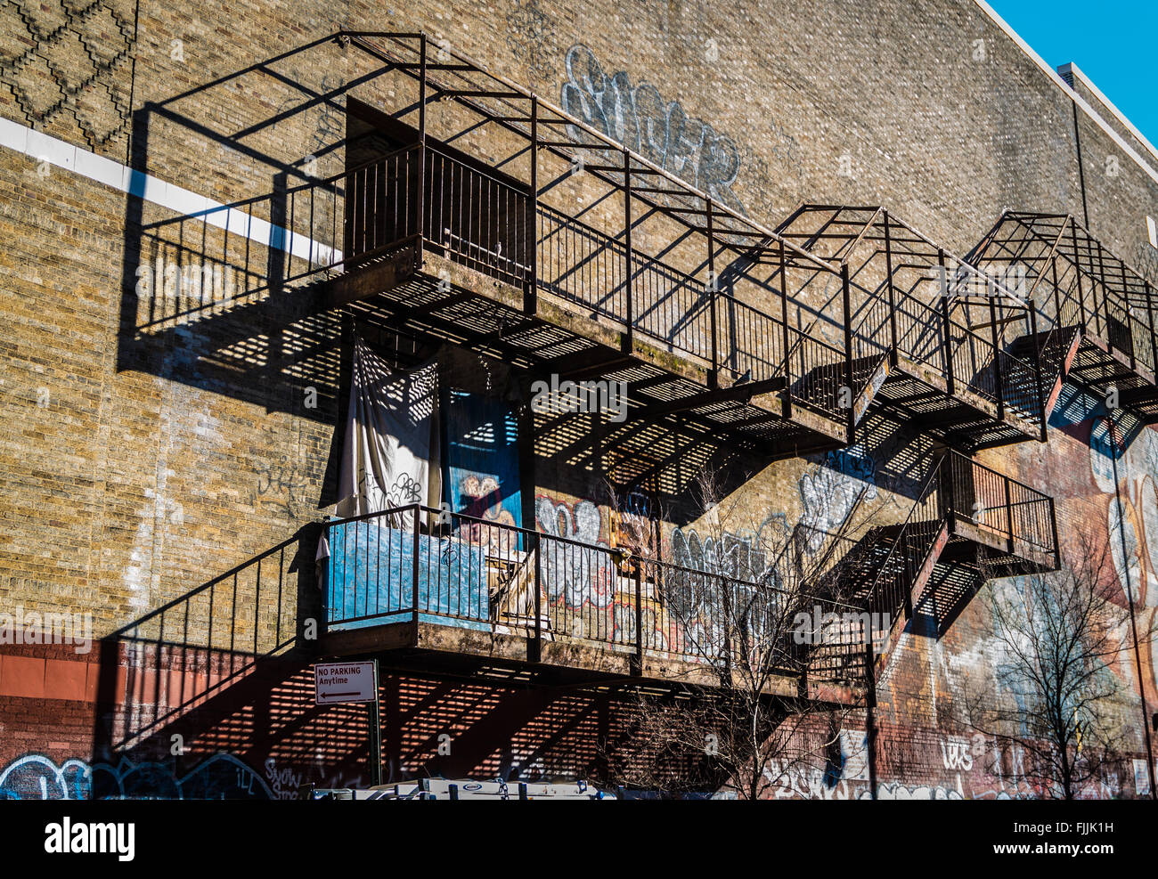 Fire fuoriesce sul lato di un edificio industriale/magazzino nella città di New York con i graffiti sulla parete in muratura. Foto Stock