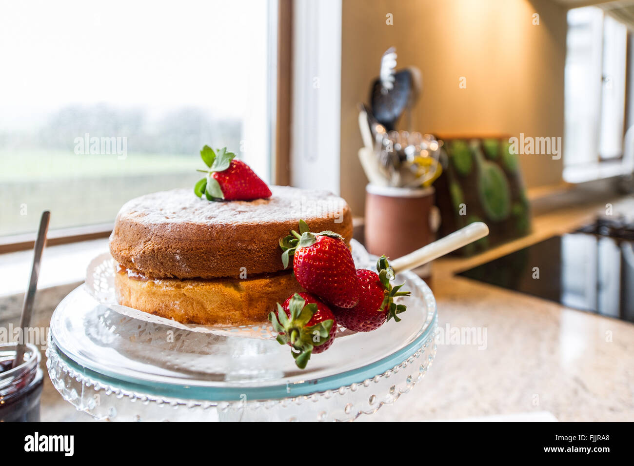 Home reso pan di spagna con le fragole su un cavalletto in una cucina domestica. Foto Stock