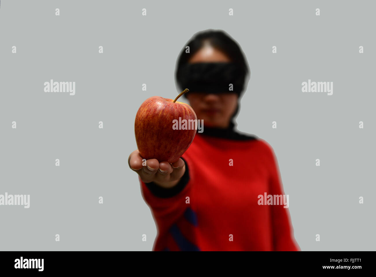 La donna gli occhi bendati su sfondo bianco e prendere un Apple Foto Stock