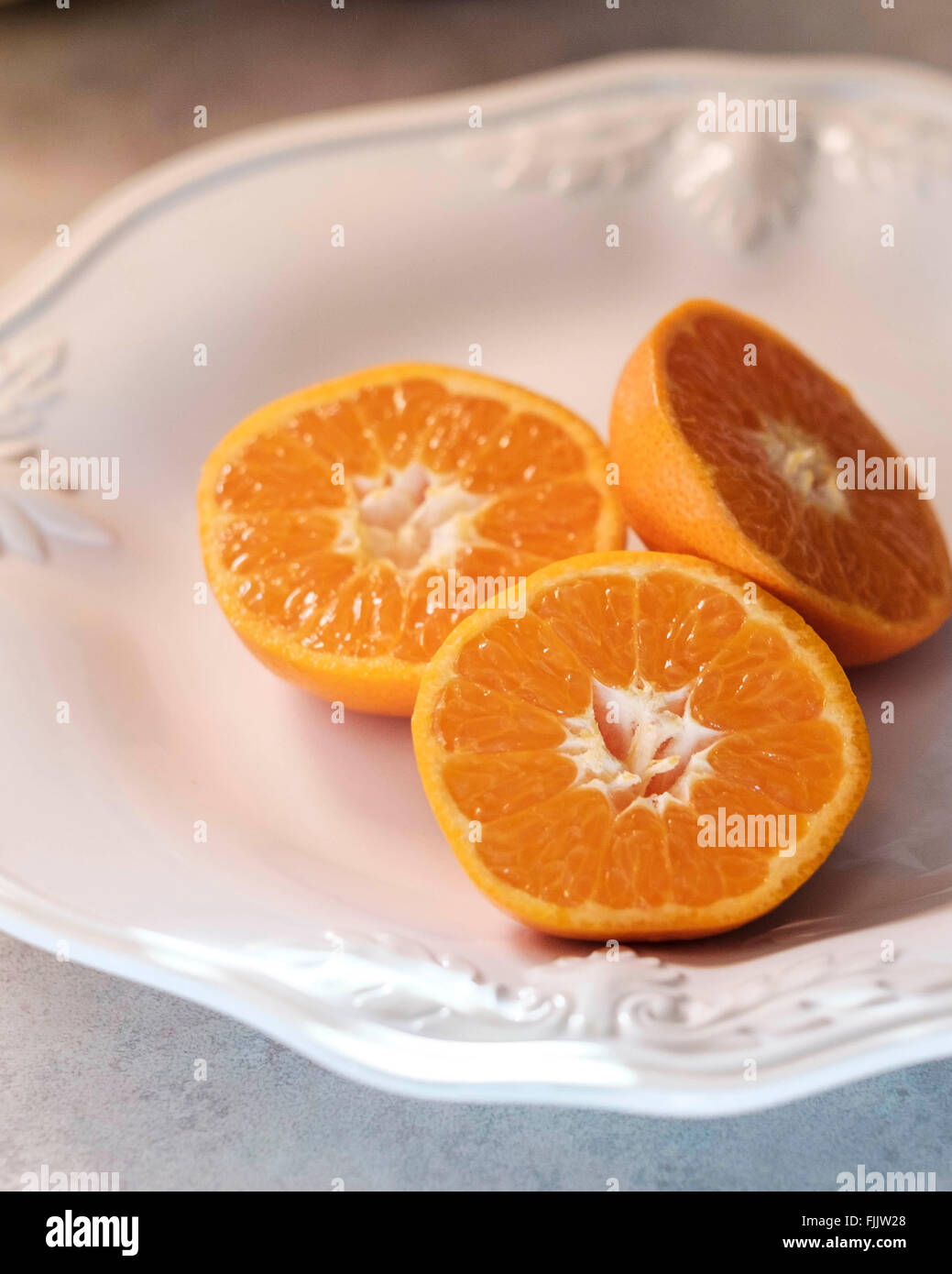 Tre metà di mandarini arance su una piastra bianca, primo piano. Foto Stock