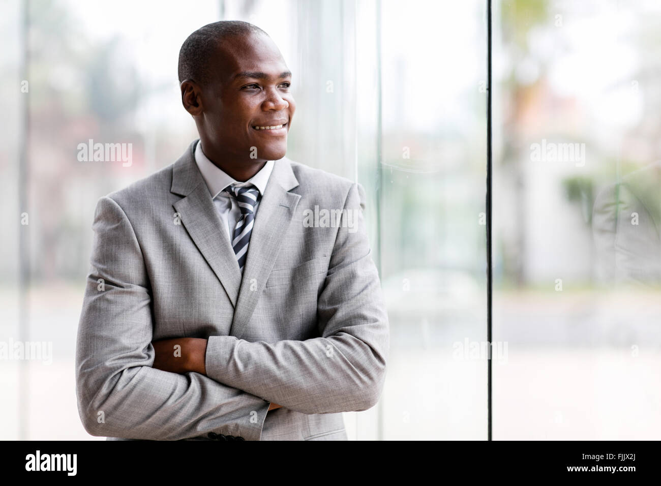 Bello imprenditore nero guardando fuori dalla finestra Foto Stock