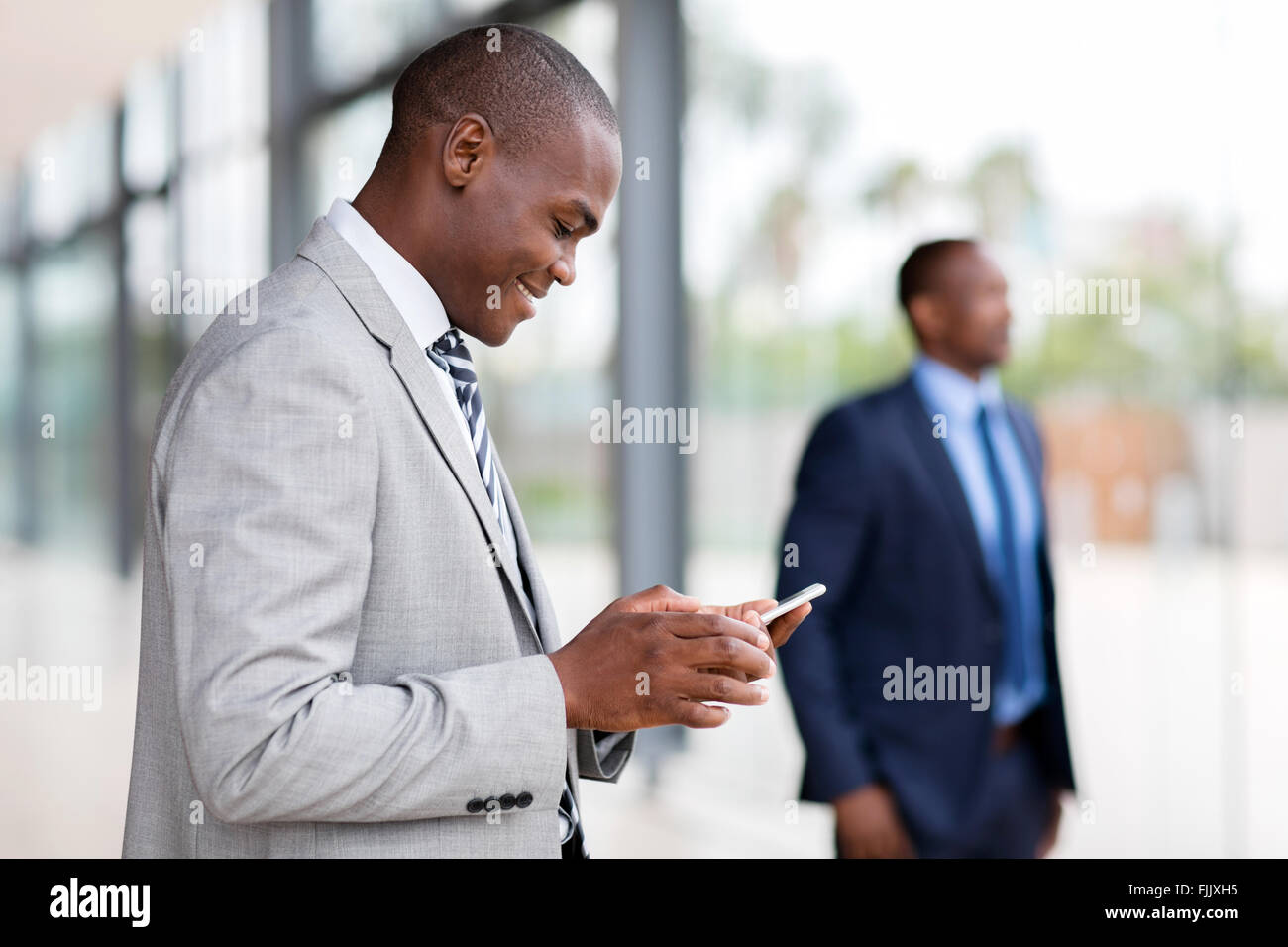 Imprenditore africana utilizzando smart phone in ufficio moderno Foto Stock