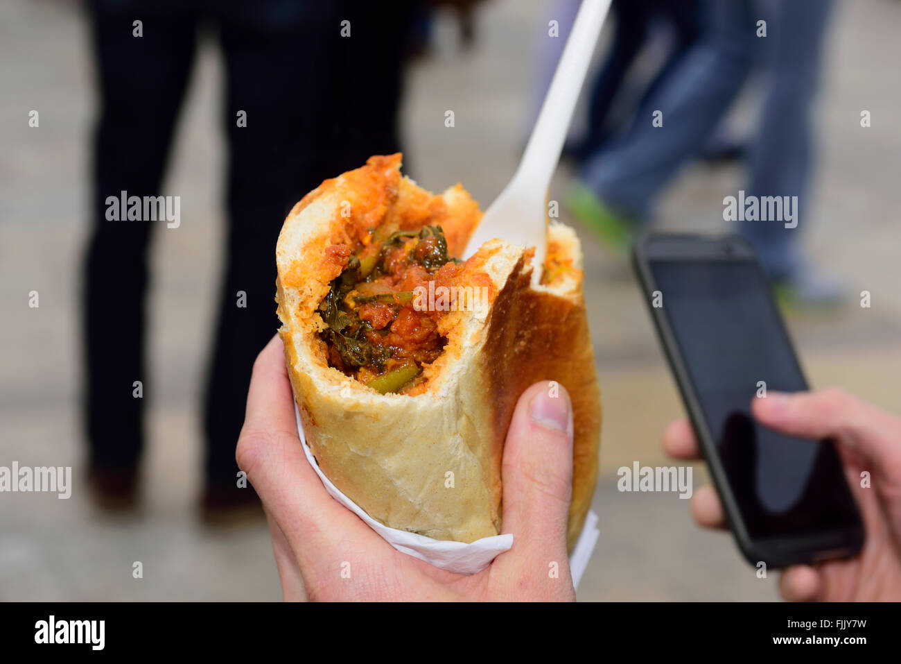 Mangiare in viaggio, mobile il telefono in mano Foto Stock