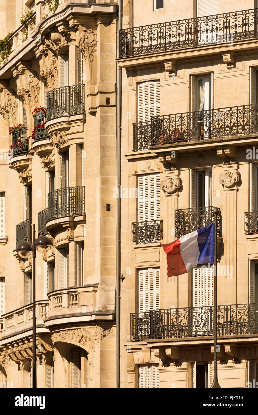 Dettaglio del tipico Hausmann-ser appartamento edificio con bandiera francese a Parigi, Francia Foto Stock