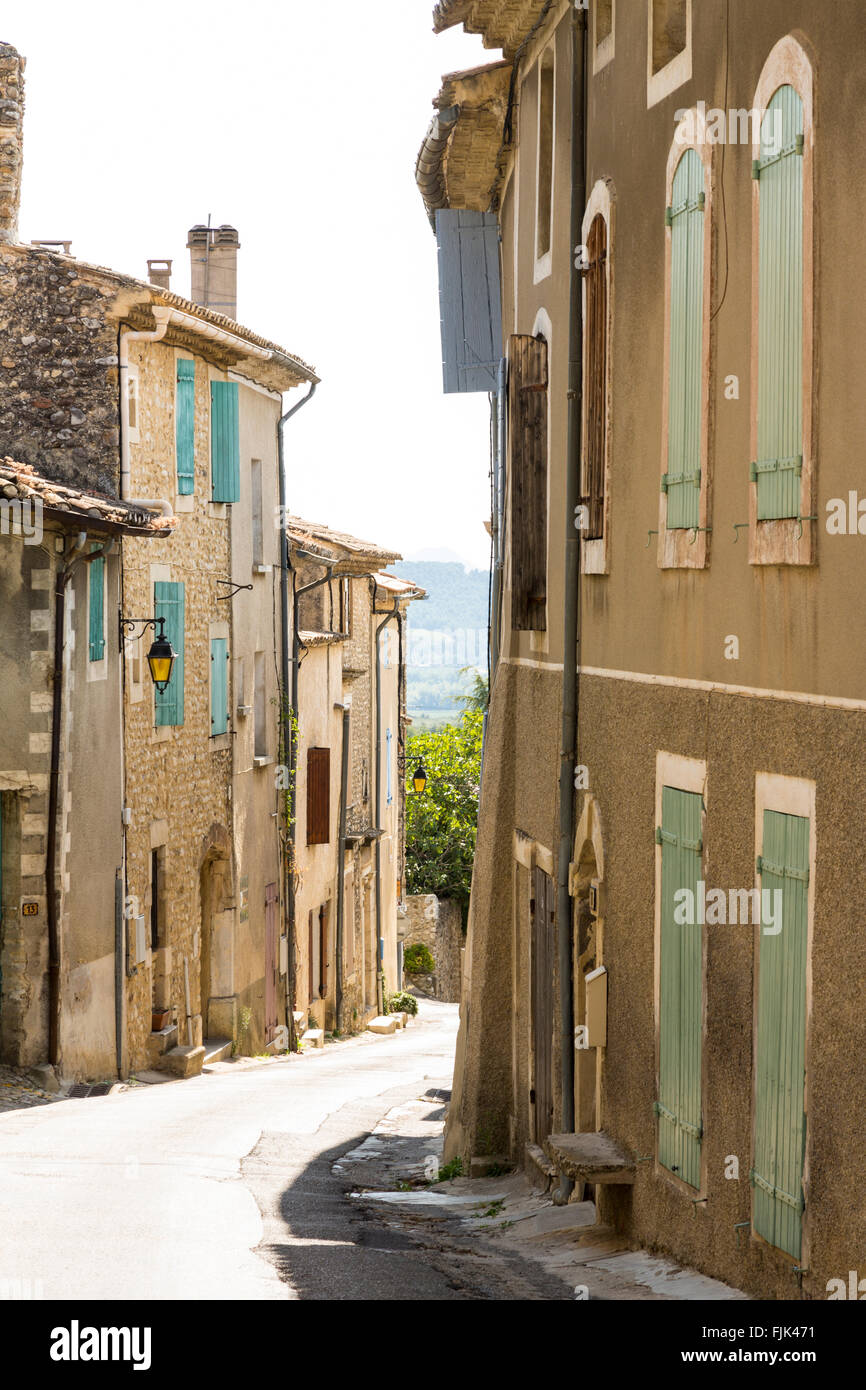 Vecchi edifici in pietra con persiane colorate su una strada stretta nel villaggio di Vinsobres, Cotes du Rhone, Provenza, Francia Foto Stock