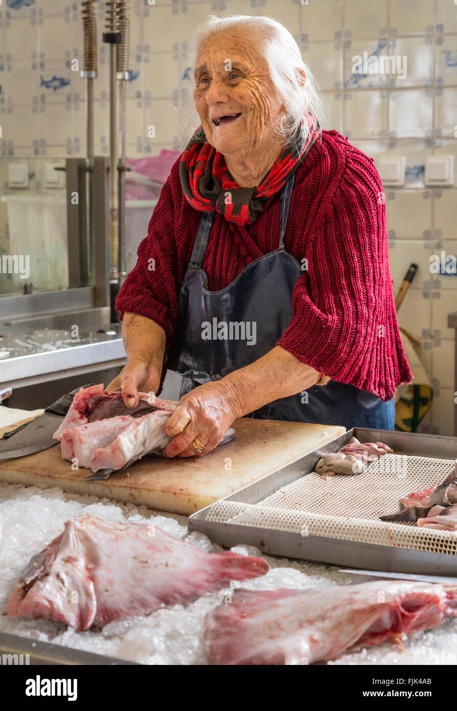 Cordiale e sorridente donna vecchio pescivendolo preparare il pesce fresco per la vendita nel mercato pubblico, Cascais, Portogallo Foto Stock