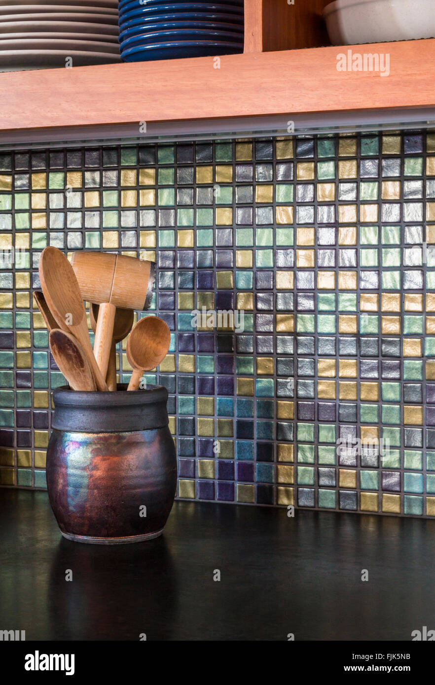 Dettaglio di alta qualità casa contemporanea cucina interno con vetro mosaico backsplash, calcestruzzo bancone in legno e utensili in ceramica raku brocca Foto Stock