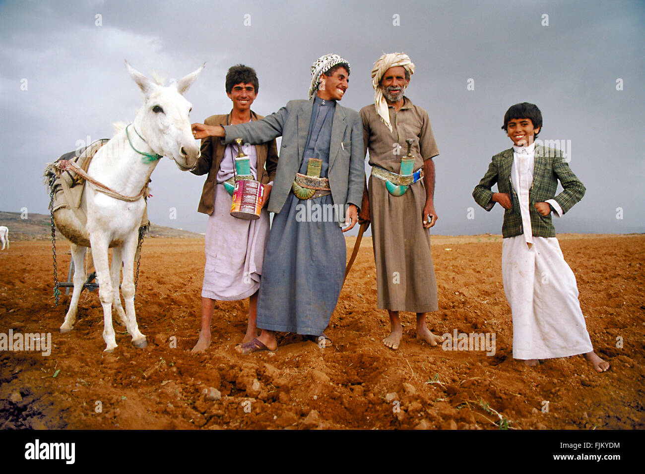 Padre e figli insieme con il loro asino in posa per il fotografo in una fattoria in Yemen. Foto Stock