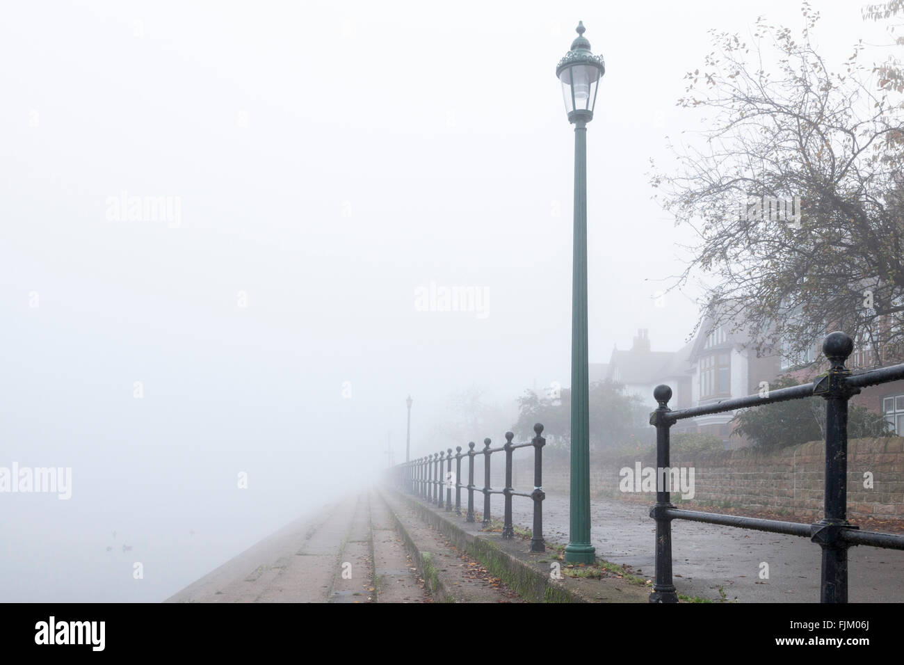 Scena di nebbia. Vecchi lampioni e ringhiere in velatura su un sentiero lungo il fiume Trent in autunno. West Bridgford, Nottinghamshire, England, Regno Unito Foto Stock