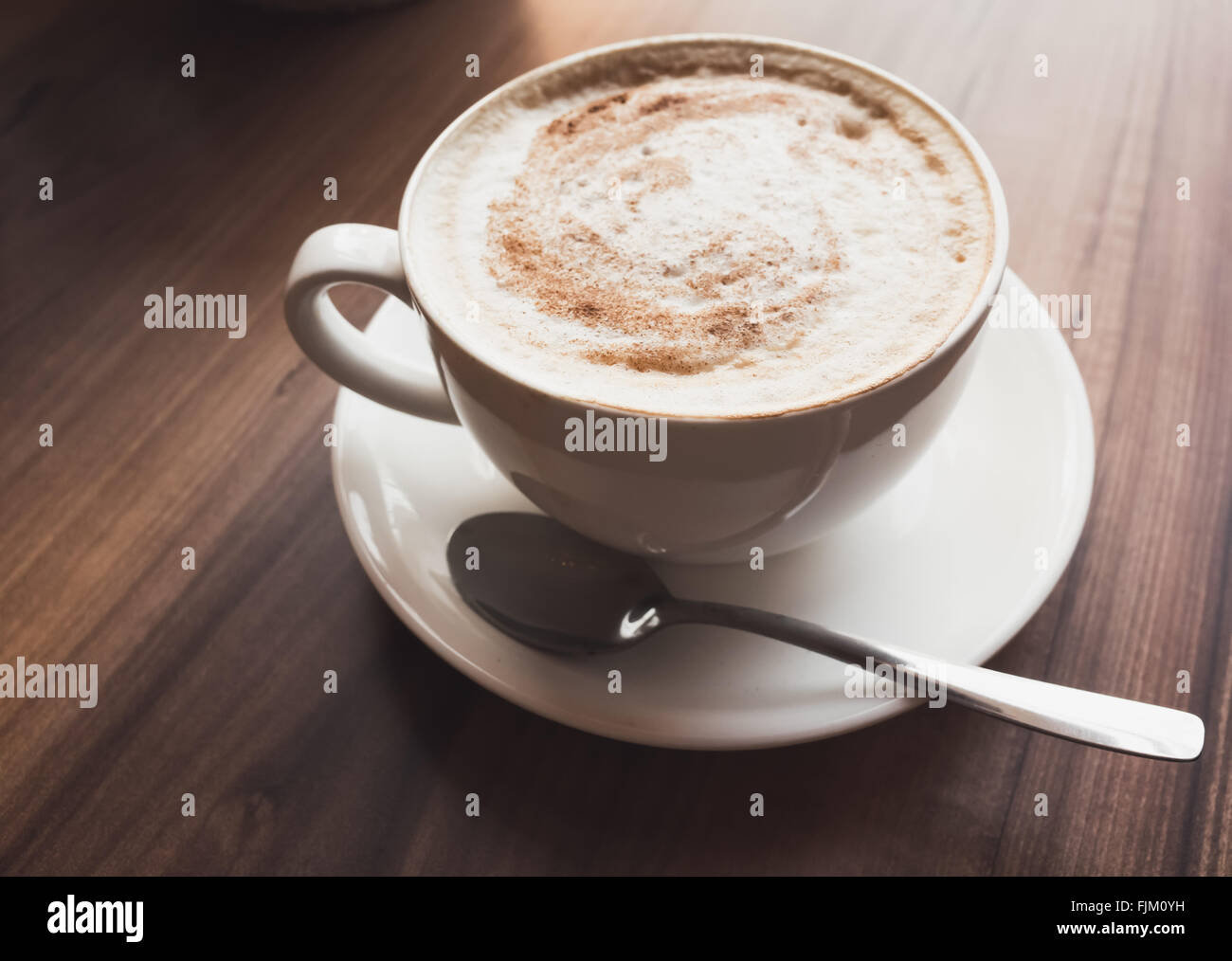 Il Cappuccino. Tazza di caffè con schiuma di latte si erge su un tavolo di legno nella caffetteria, vintage la correzione delle tonalità filtro foto, vecchio stile e Foto Stock