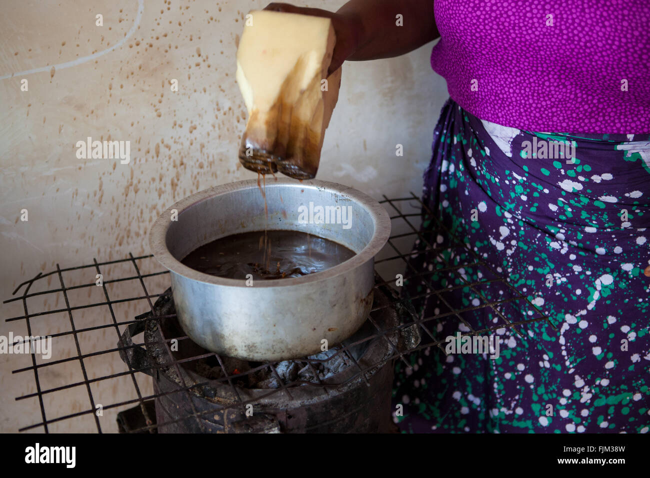 Una donna di inchiostro di riscaldamento da utilizzare per legare die panno, Tanzania Foto Stock