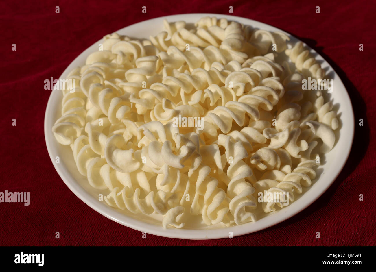 Gustosi spuntini leggeri/patatine in piastra bianca su sfondo rosso Foto Stock