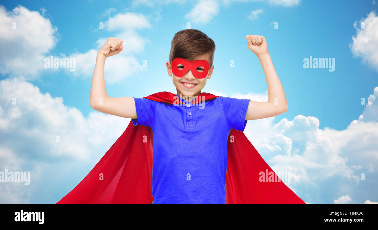 Ragazzo in rosso super hero cape e la maschera che mostra a suon di pugni Foto Stock