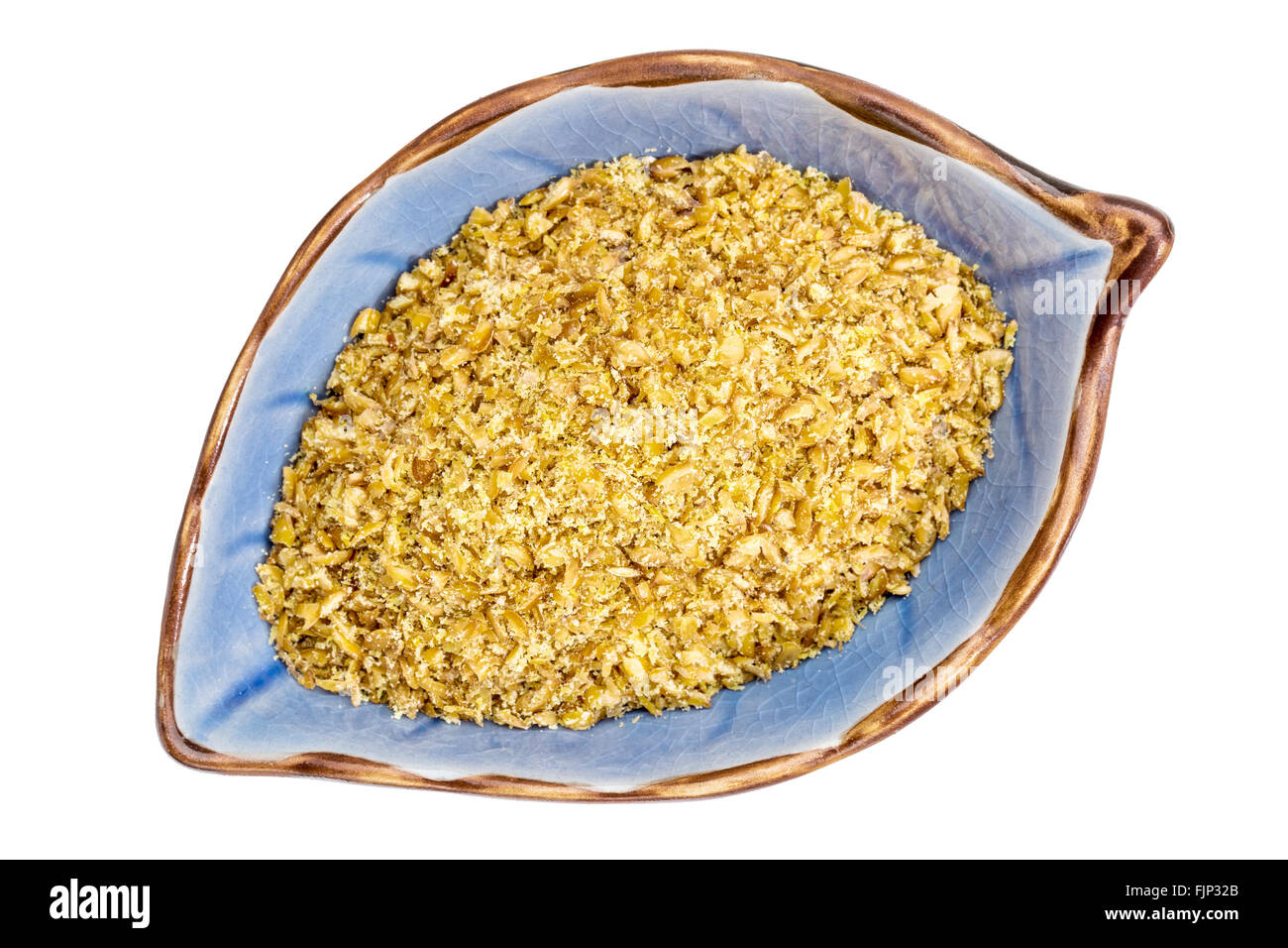 Golden farina di lino in una lamina a forma di coppa in ceramica isolata su bianco Foto Stock