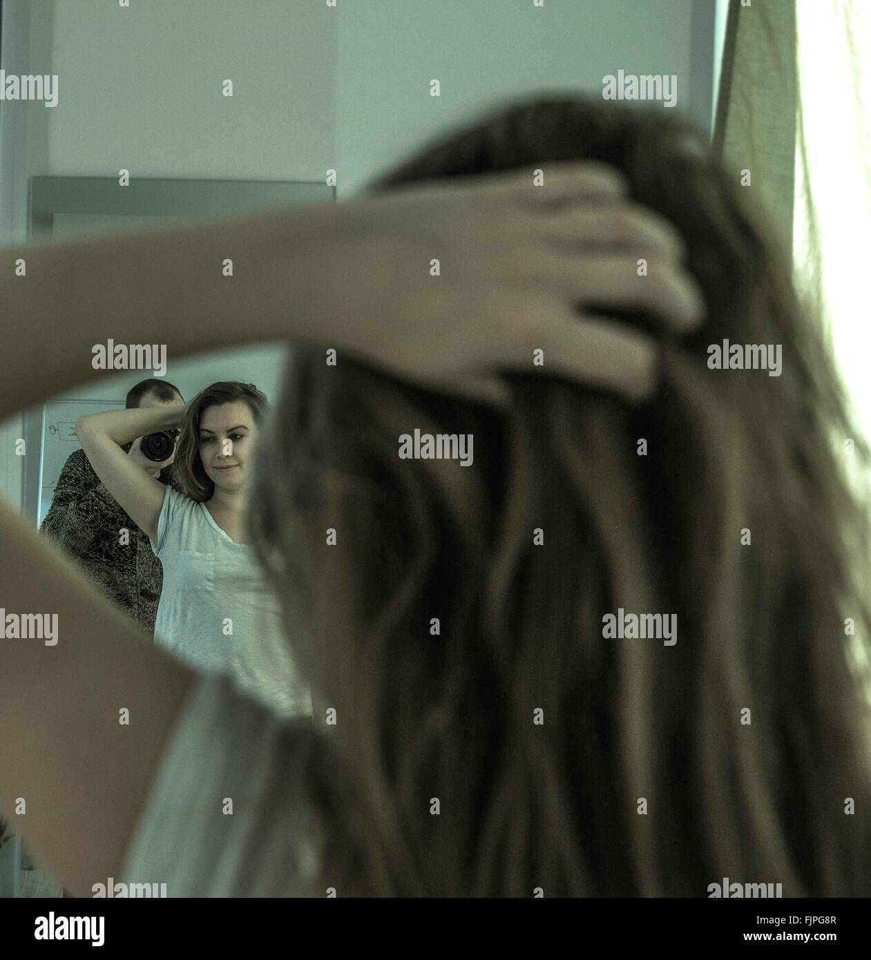 Uomo Donna fotografare con le mani nei capelli mentre riflette sullo specchio a casa Foto Stock