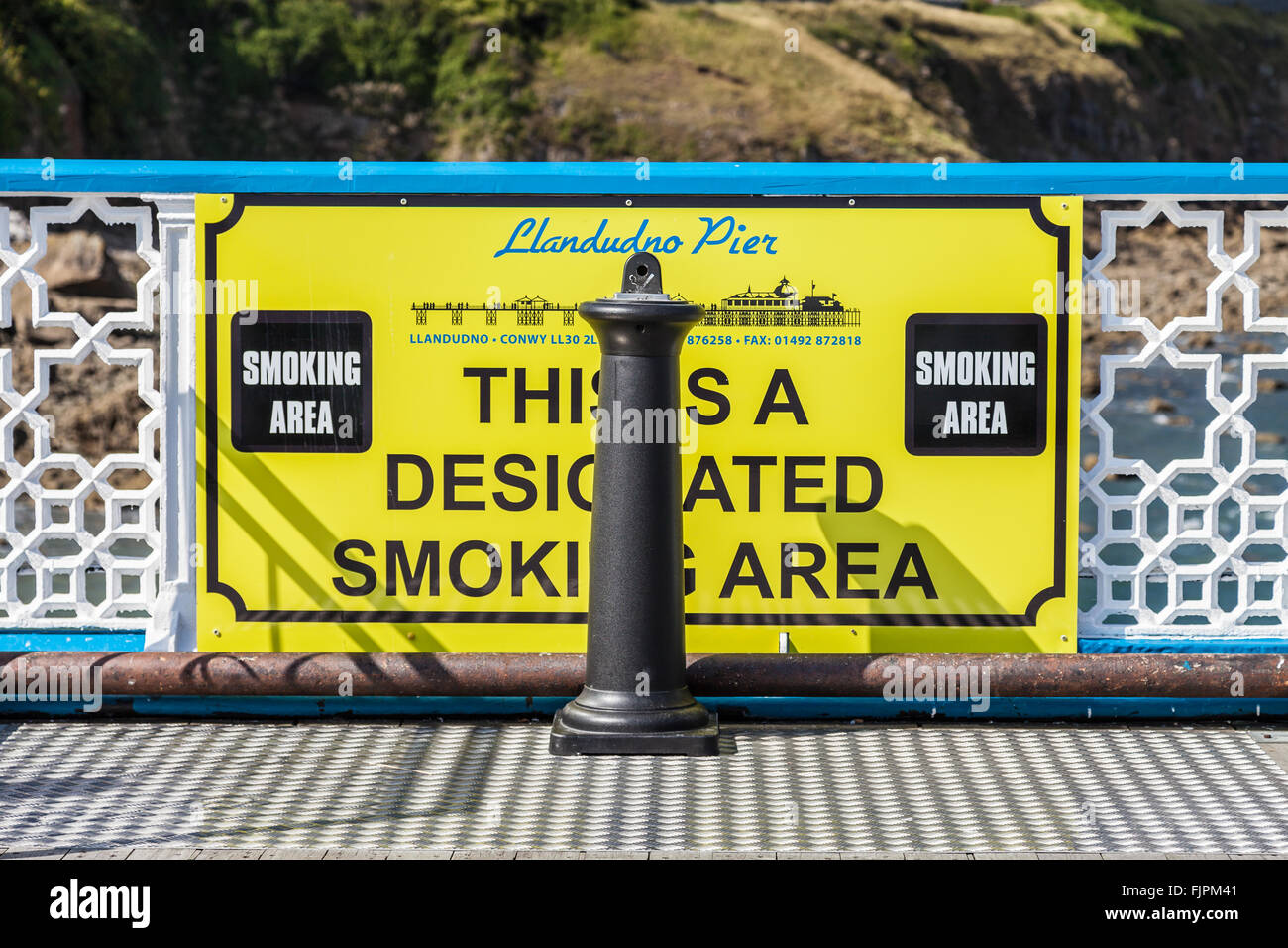 Giallo bacheca sul Llandudno Pier informare la gente di una zona designata zona fumatori. Llandudno, Galles, Gran Bretagna. Foto Stock