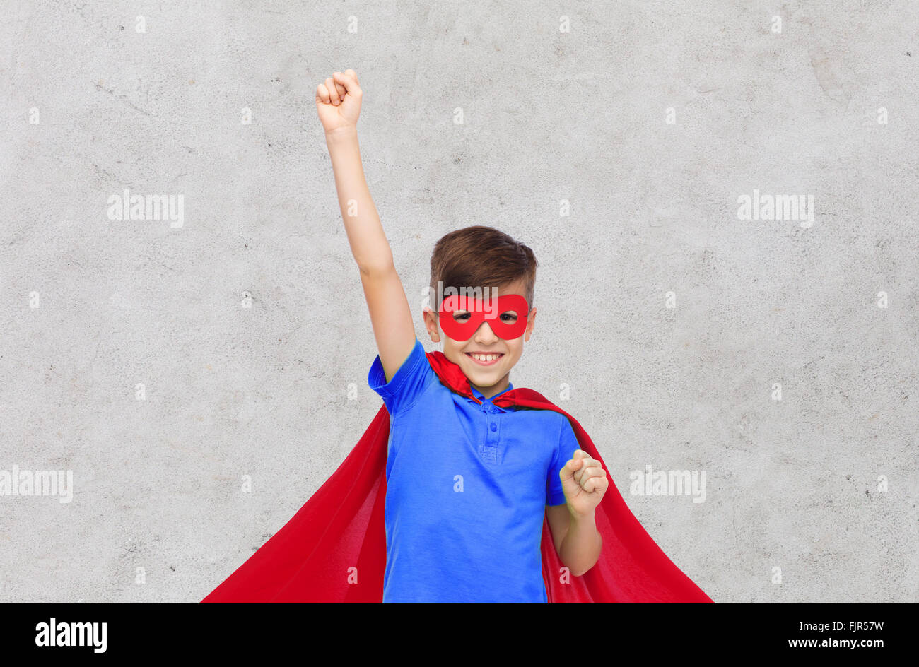 Ragazzo in rosso superhero cape e la maschera che mostra a suon di pugni Foto Stock