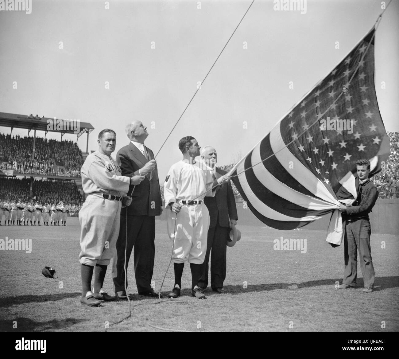 Joe McCarthy, direttore Yankee di New York, il Postmaster generale James A. Farley, il senatore di Washington Bucky Harris, e Clark Griffith, proprietario dei senatori, che elevano la bandiera americana prima della prima partita di baseball della stagione, Griffith Stadium, Washington DC, USA, Harris & Ewing, Aprile 21, 1939 Foto Stock