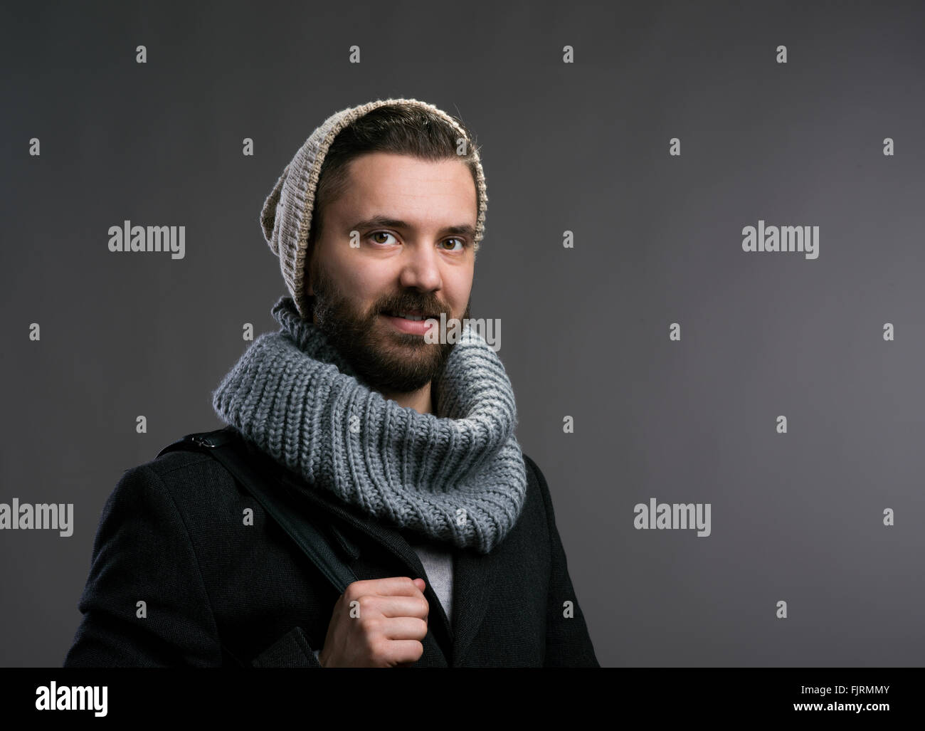 Uomo in cappotto, sciarpa e beanie. Studio shot Foto Stock