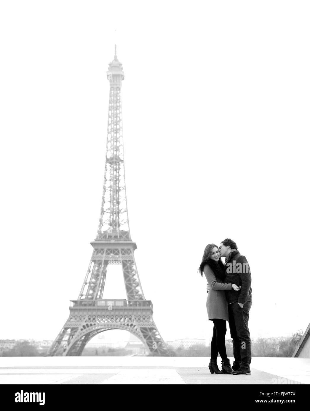 Giovane e in amore bruna giovane di fronte alla torre Eiffel, Parigi, al Trocadero che domina la città durante il giorno Foto Stock