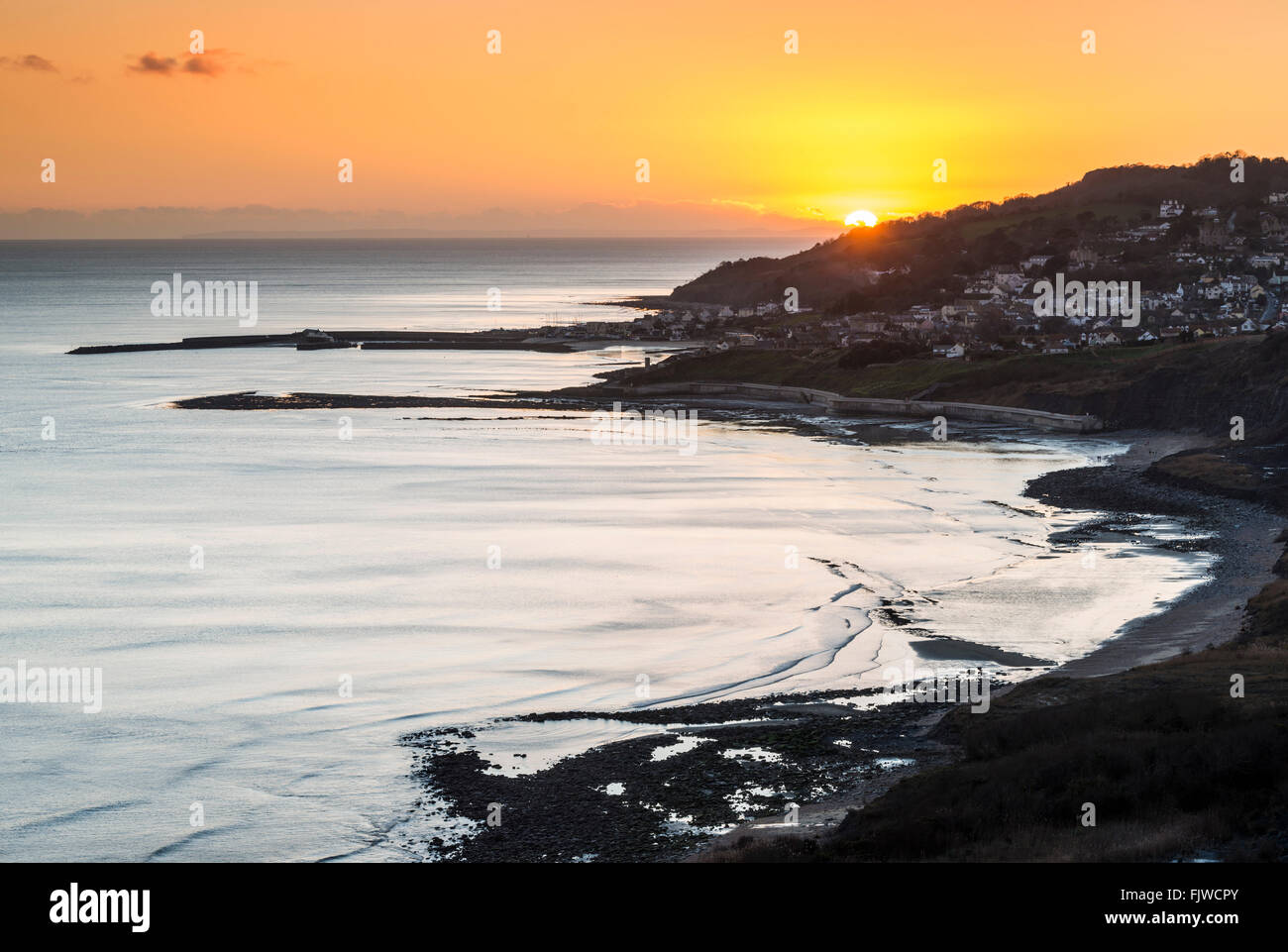 Il sole che tramonta sulla Lyme Regis visto dal Charmouth su Dorset la Jurassic Coast, REGNO UNITO Foto Stock