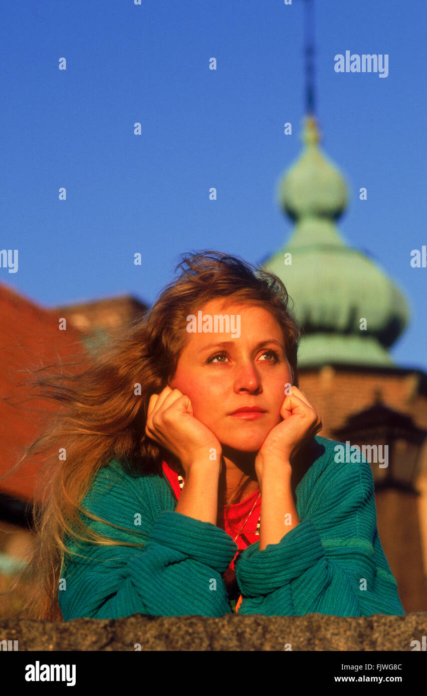 Viso sano e fresco di donna che indossa pullover colorato Fronte del muro con campanile della chiesa a Stoccolma Foto Stock