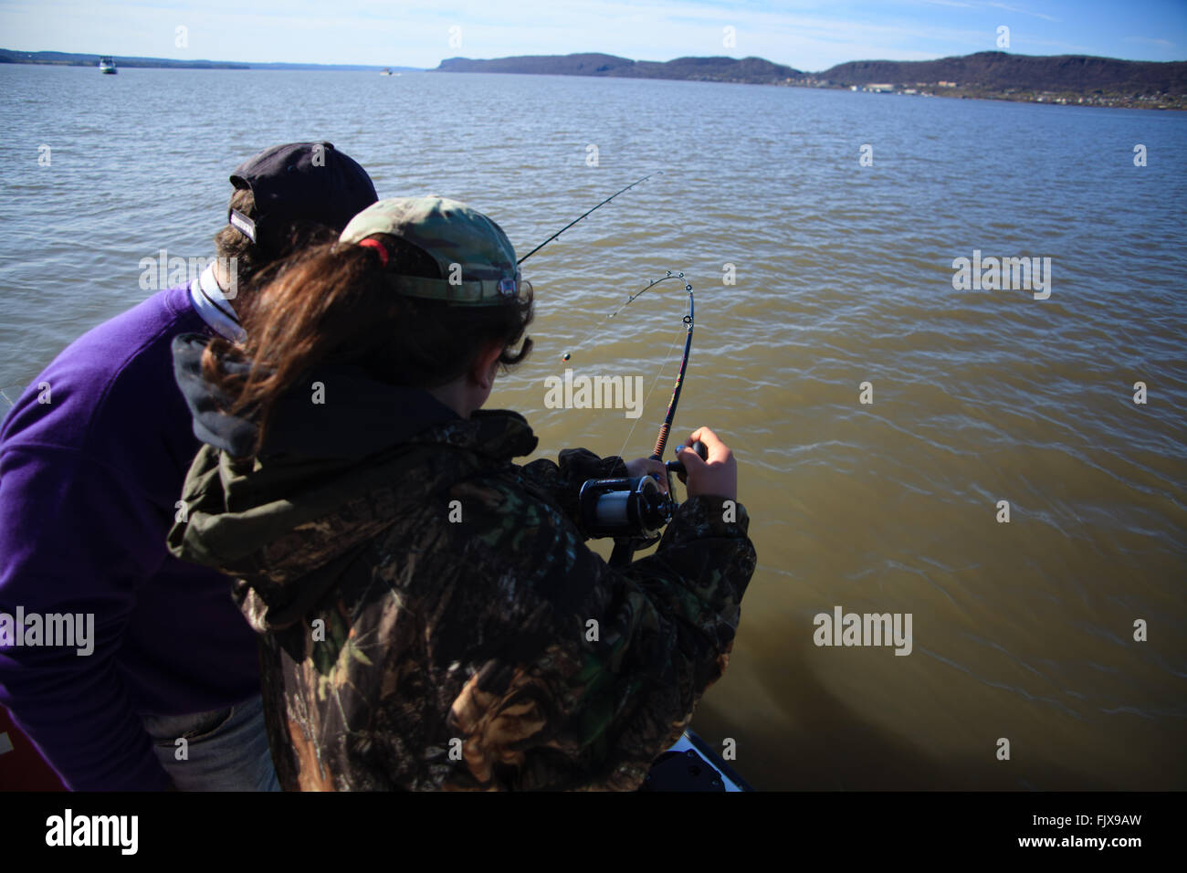 Ragazza giovane la bobinatura in un pesce fuori dalla parte laterale di una barca sul fiume Hudson, New York. Foto Stock