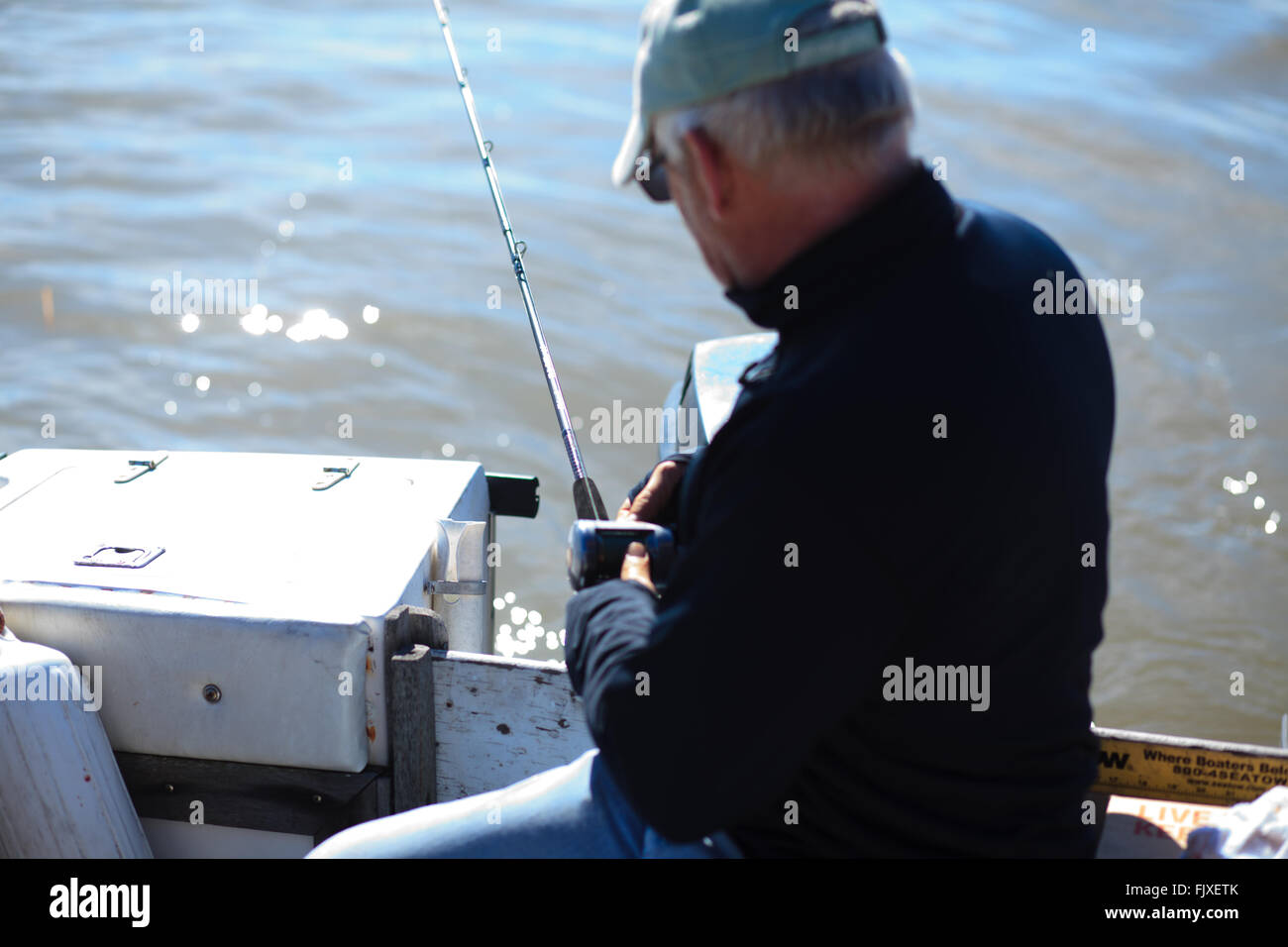 L'uomo lasciando fuori linea della canna da pesca sul retro di una barca Foto Stock