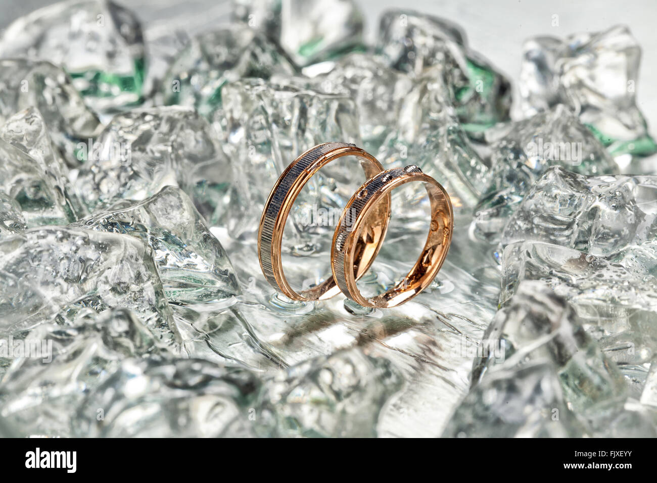 Due golden anelli di fidanzamento nel ghiaccio con gocce d'acqua Foto Stock