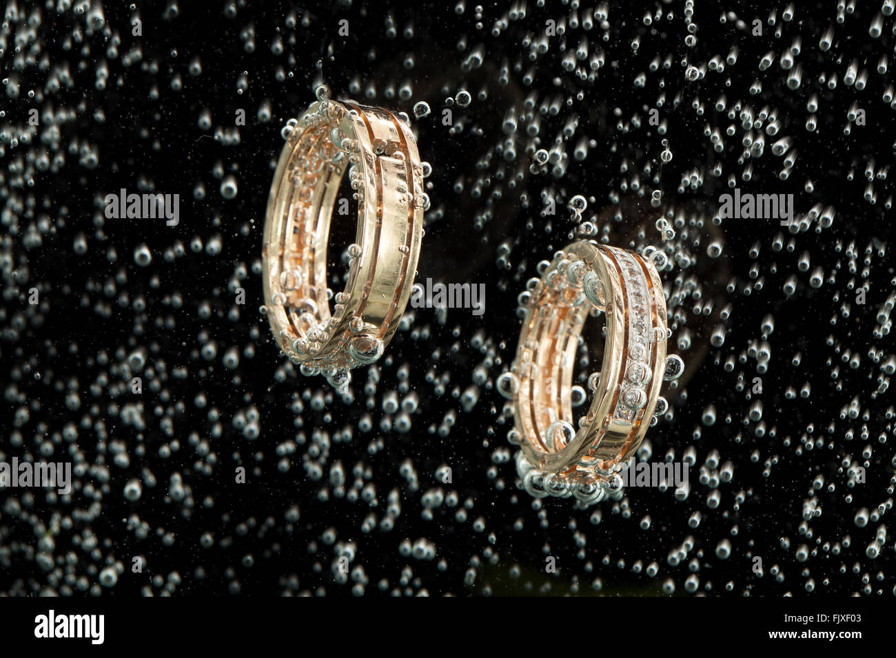 Impegno di due anelli d oro in acqua con bolle di aria Foto Stock
