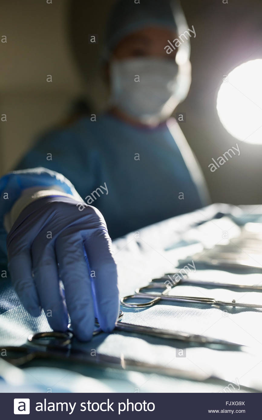 Chirurgo Plastico raggiungendo per forbici chirurgiche in sala operatoria Foto Stock
