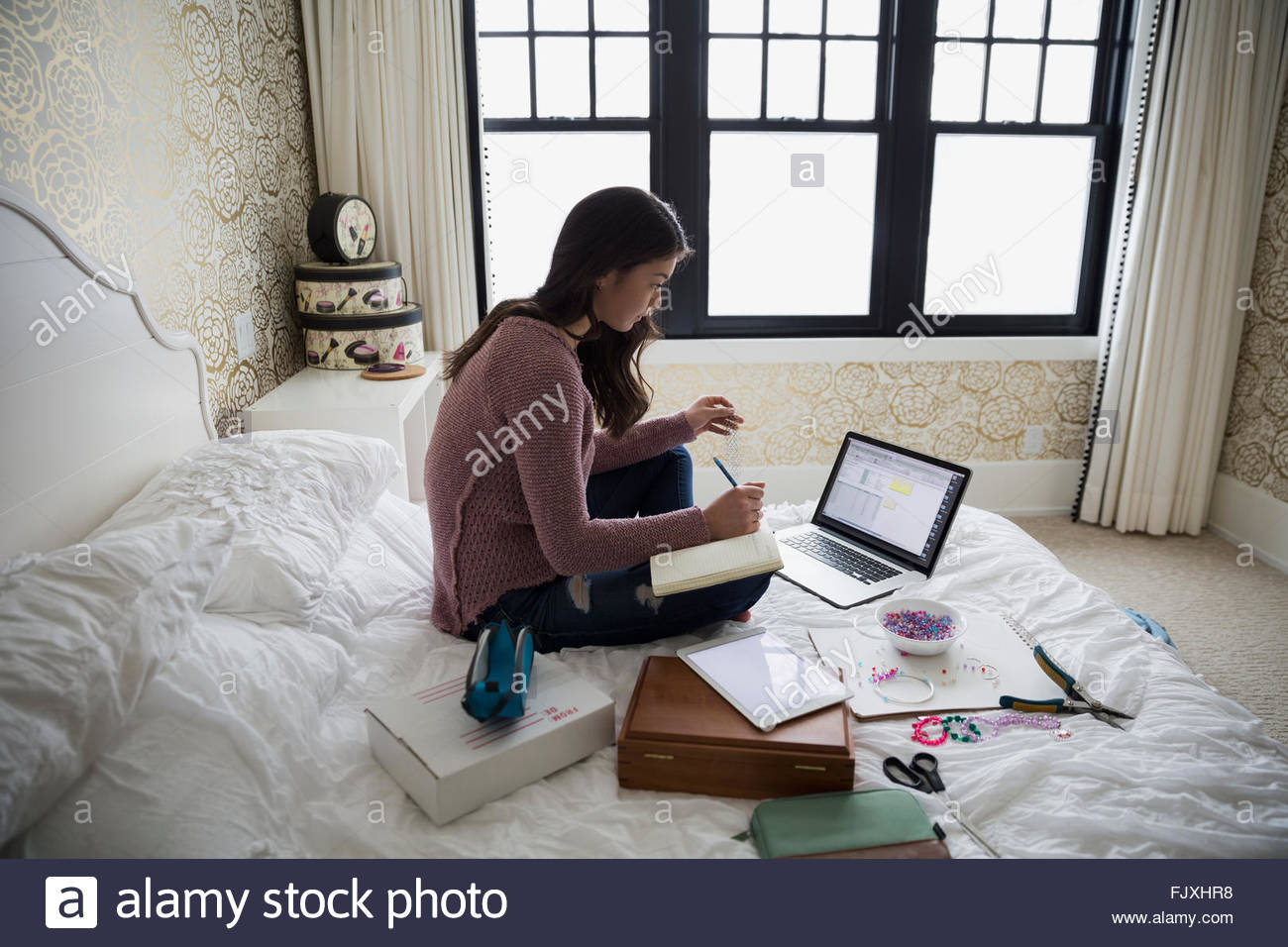 Ragazza adolescente pianificazione trucco gioielli al laptop Foto Stock