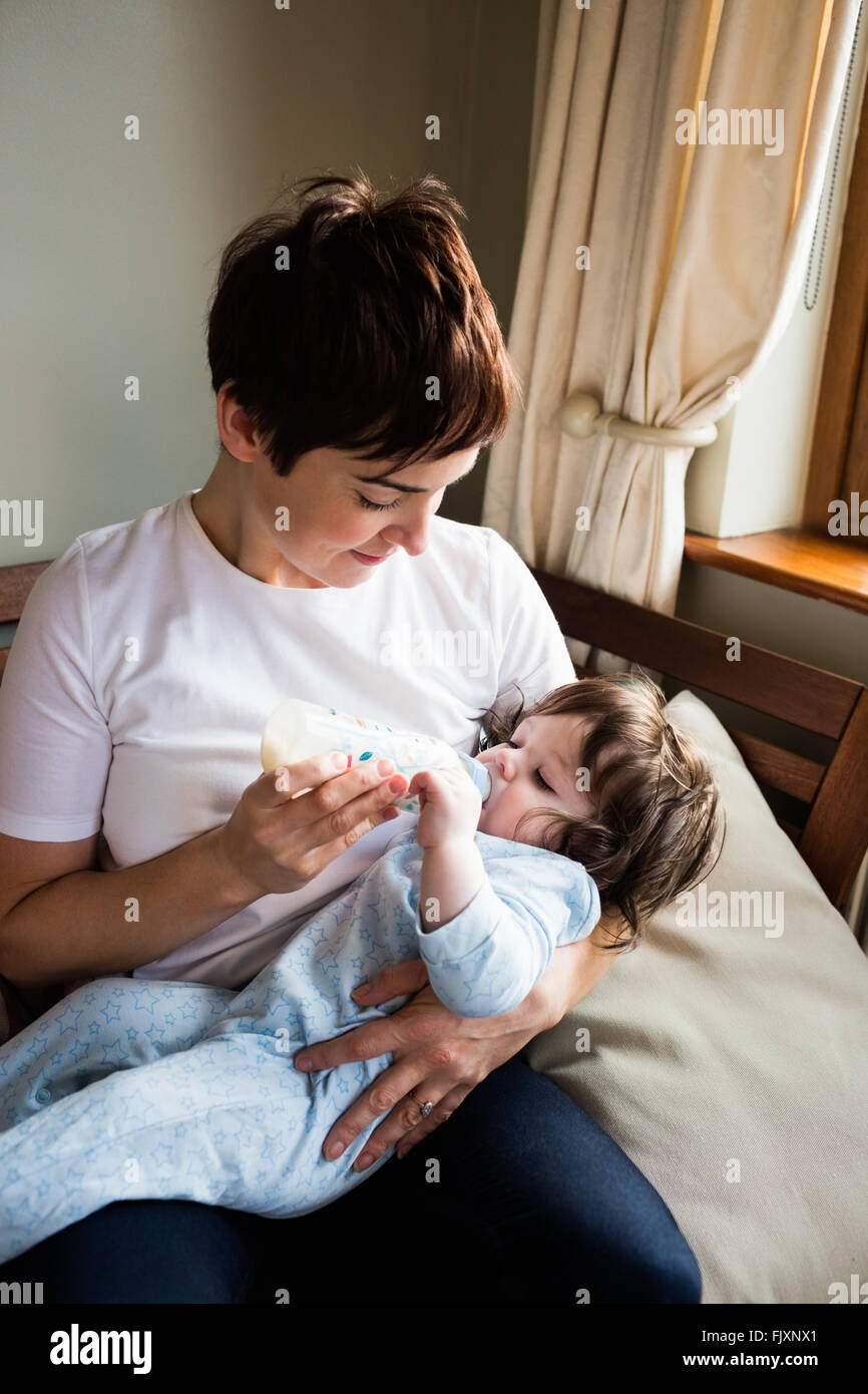 Carino madre allattamento al biberon il suo bambino Foto Stock