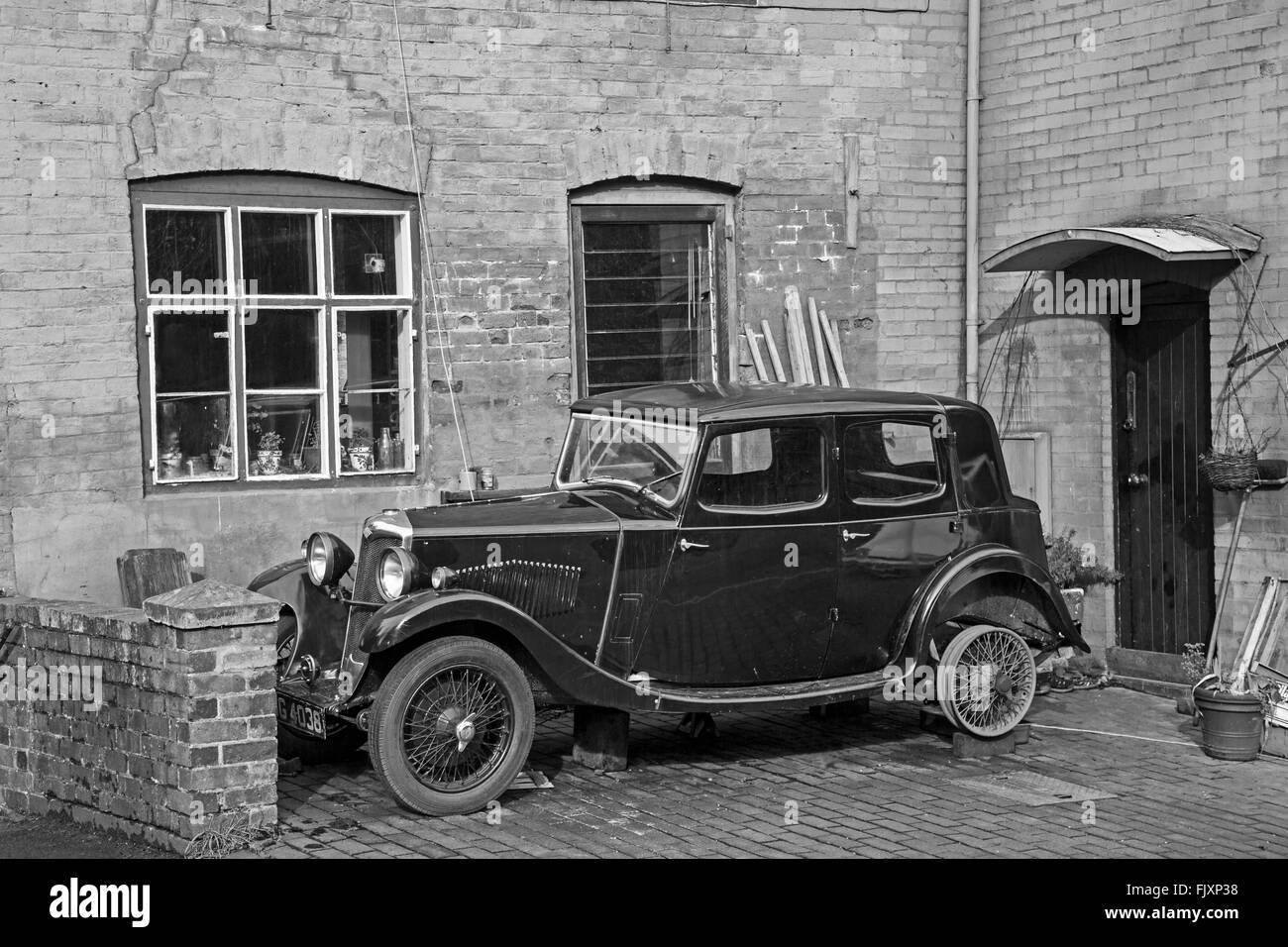 Vintage Riley auto sotto la riparazione, parcheggiata fuori casa. Foto moderna convertito in bianco e nero. Foto Stock