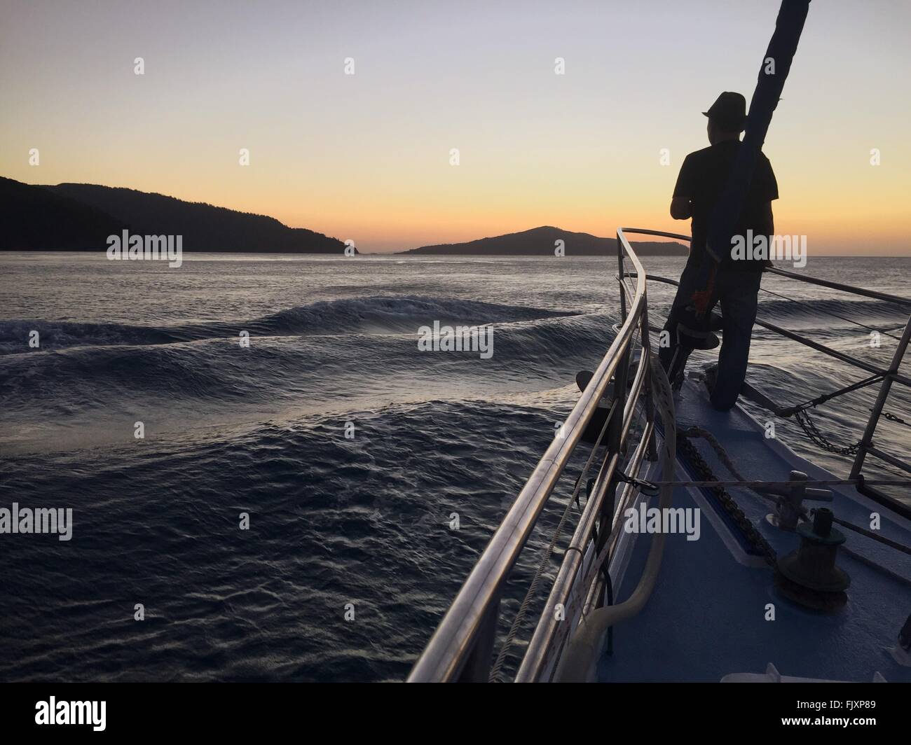 Vista posteriore dell'uomo sulla barca in mare contro il cielo durante il tramonto Foto Stock