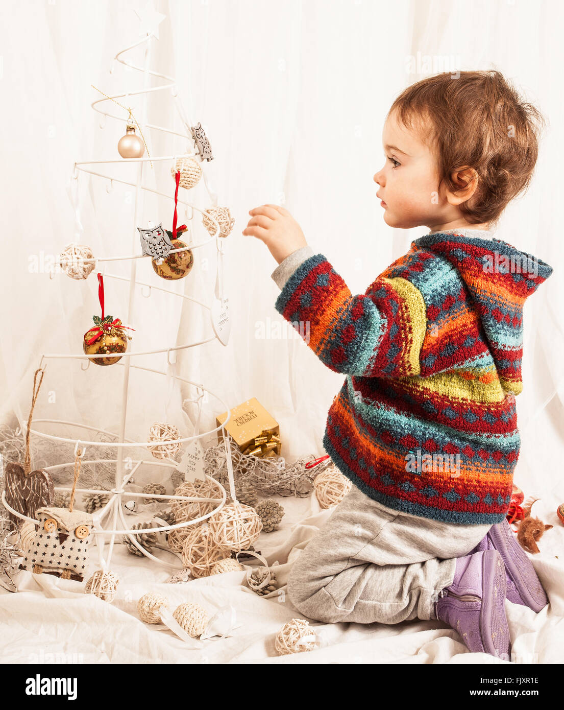 Ragazzo giocando con decorazione di Natale sul letto di casa Foto Stock
