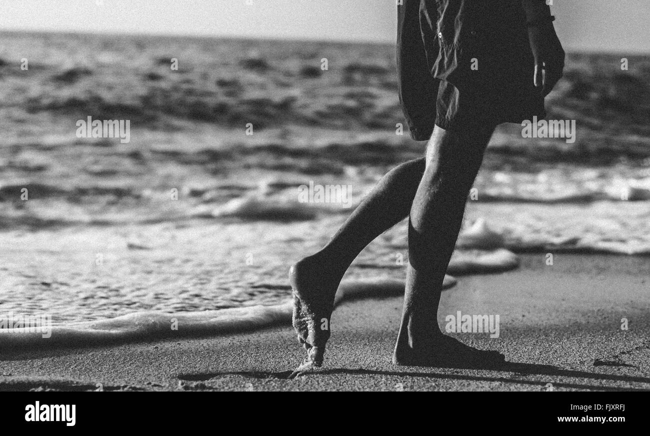 Sezione bassa della Donna che cammina in riva al mare Foto stock - Alamy