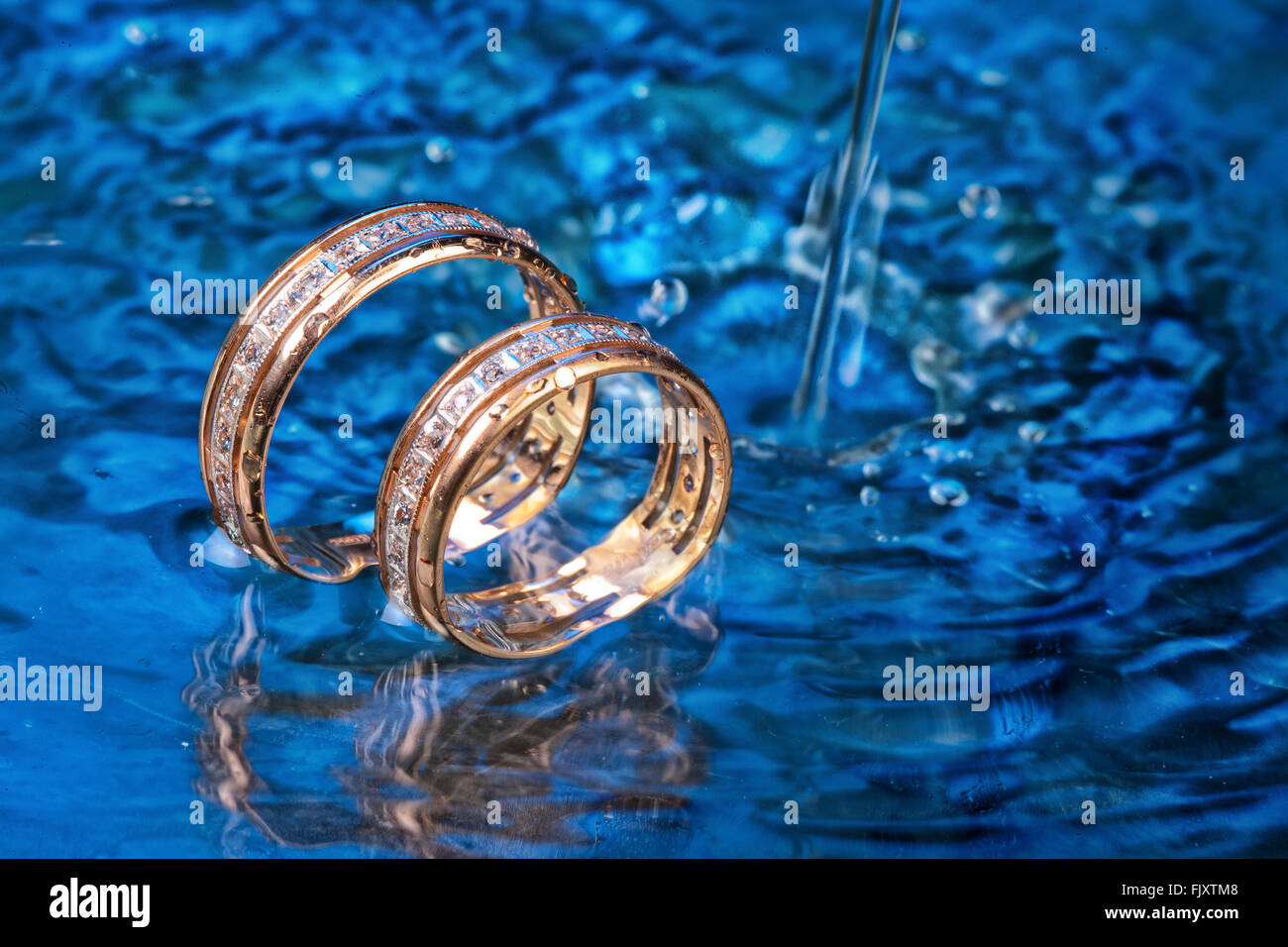 Impegno di due anelli d oro in acqua con bolle di aria Foto Stock