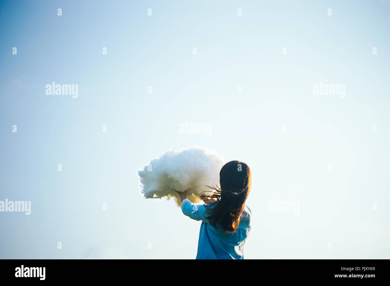 Vista posteriore della donna tenendo il Cloud contro il cielo chiaro Foto Stock