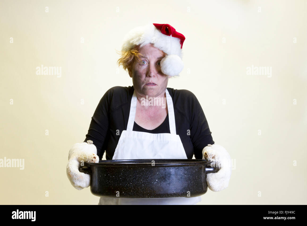 Donna matura con firmato faccia tenendo teglia con santa hat e grembiule. Foto Stock