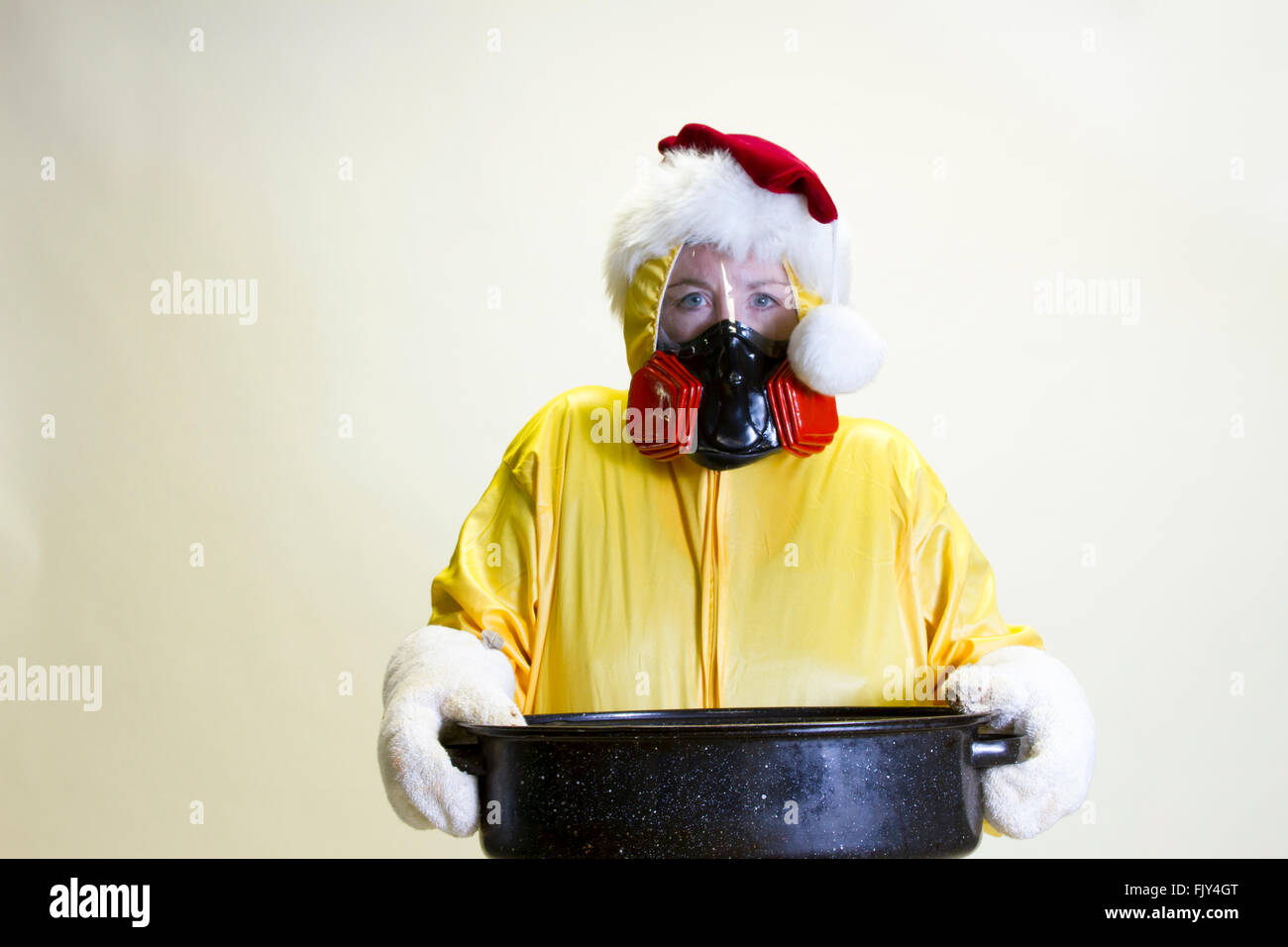 Donna matura in giallo hazmat suit e calza hat holding teglia. Foto Stock