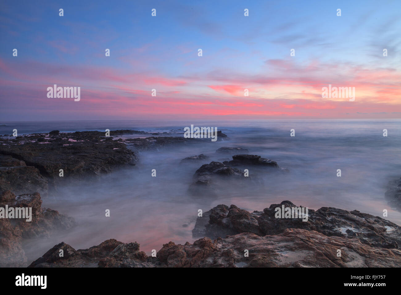 Una lunga esposizione del tramonto su rocce, dando una nebbia simile effetto sull'oceano in Laguna Beach, California, Stati Uniti Foto Stock