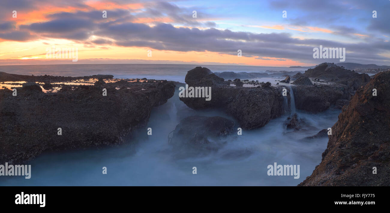 Una lunga esposizione del tramonto su rocce, dando una nebbia simile effetto sull'oceano in Laguna Beach, California, Stati Uniti Foto Stock