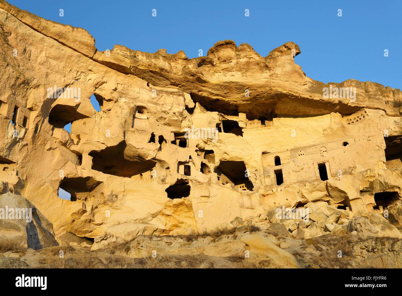 Parte della scogliera abitazione complesso di antiche chiese cristiane e case nel villaggio di Cavusin vicino a Goreme, Cappadocia, Turchia Foto Stock