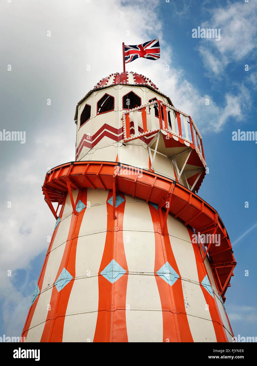 Vintage Helter Skelter Fairground Ride in estate con la bandiera europea, dipinta di arancione e crema di latte Foto Stock